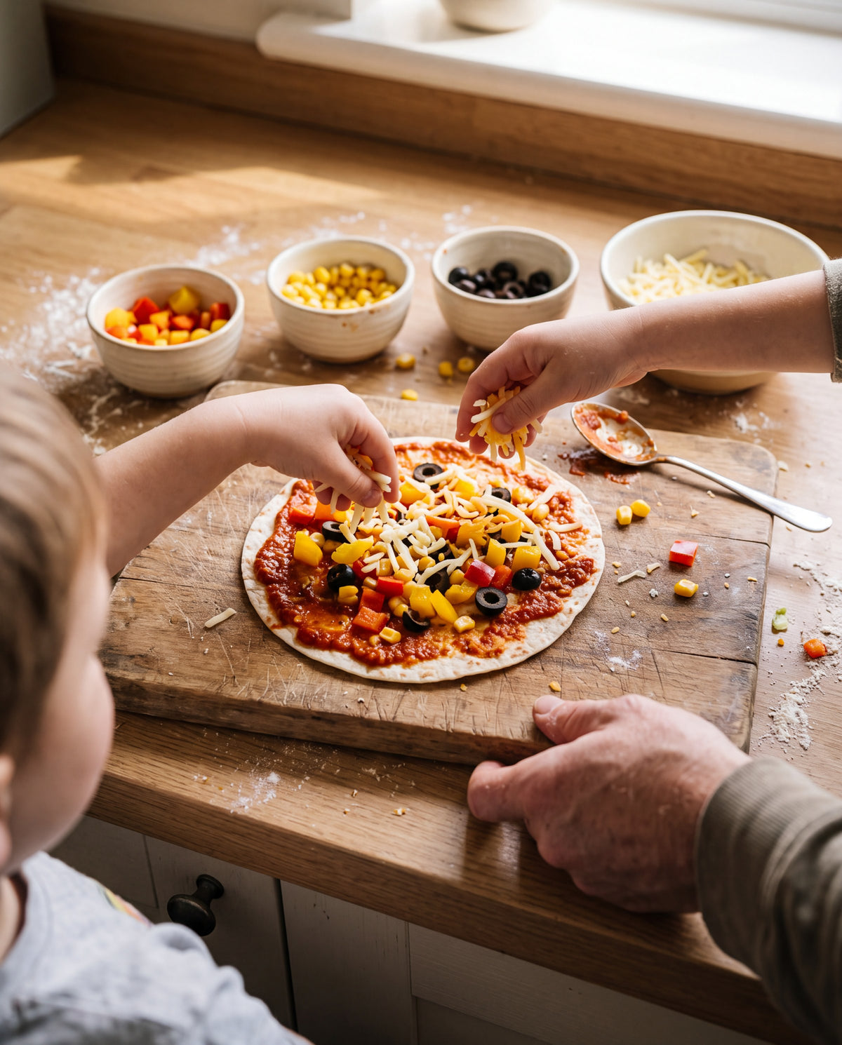 Kids adding toppings to a tortilla pizza while a parent holds the board