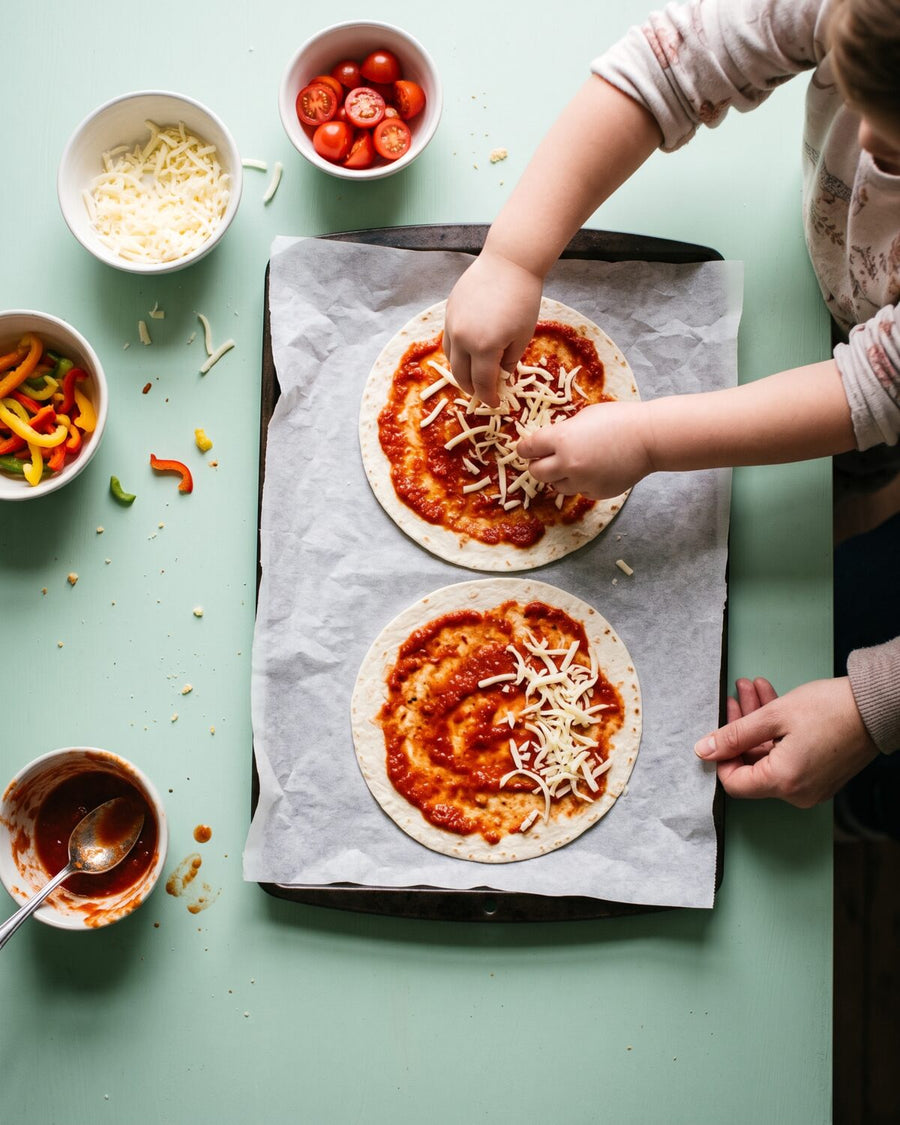 A small child sprinkles cheese on tortilla pizzas