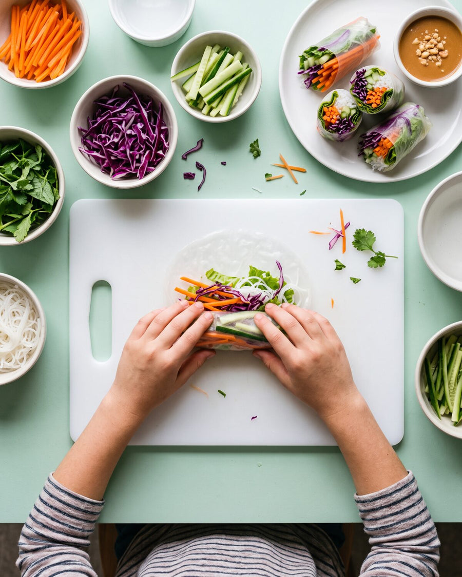 An older child rolls a rainbow spring roll